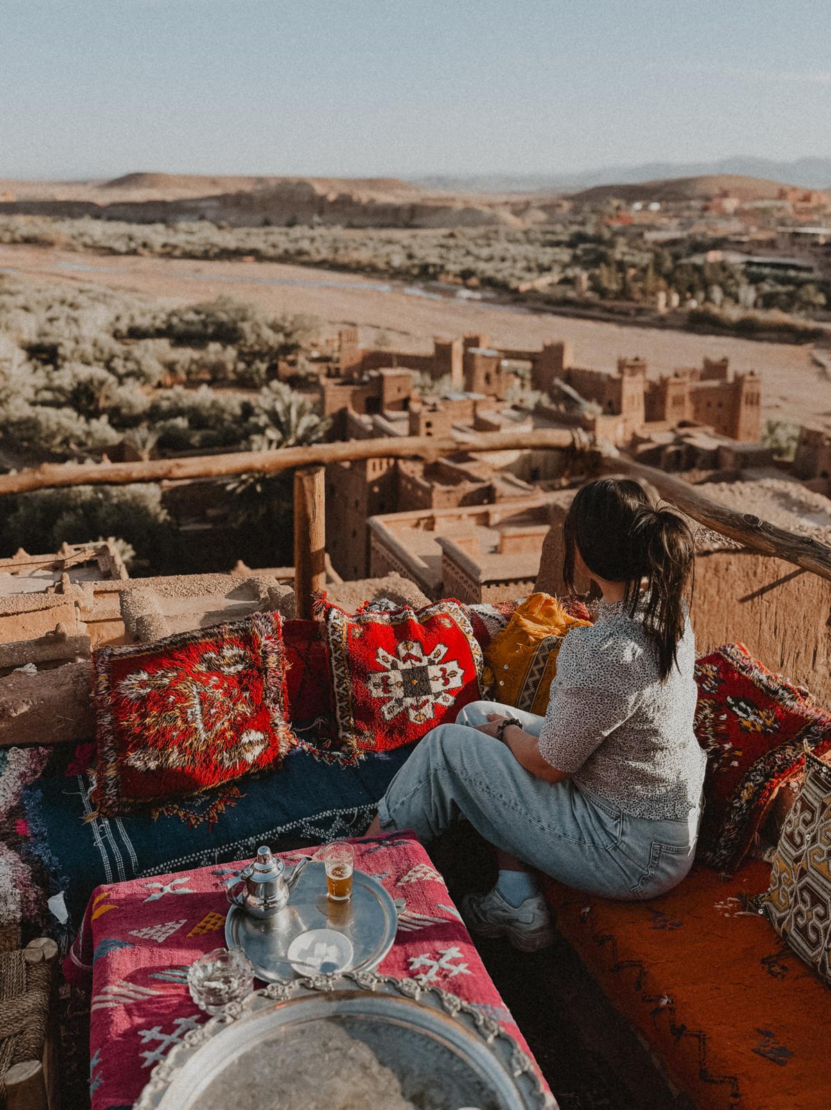 Kleines Café auf dem Dach eines Hauses in Ait Ben Haddou, mit atemberaubendem Blick über das historische Dorf und die umliegende Wüstenlandschaft. Das Café bietet eine entspannte Atmosphäre, um die Aussicht bei einem erfrischenden Minztee zu genießen.