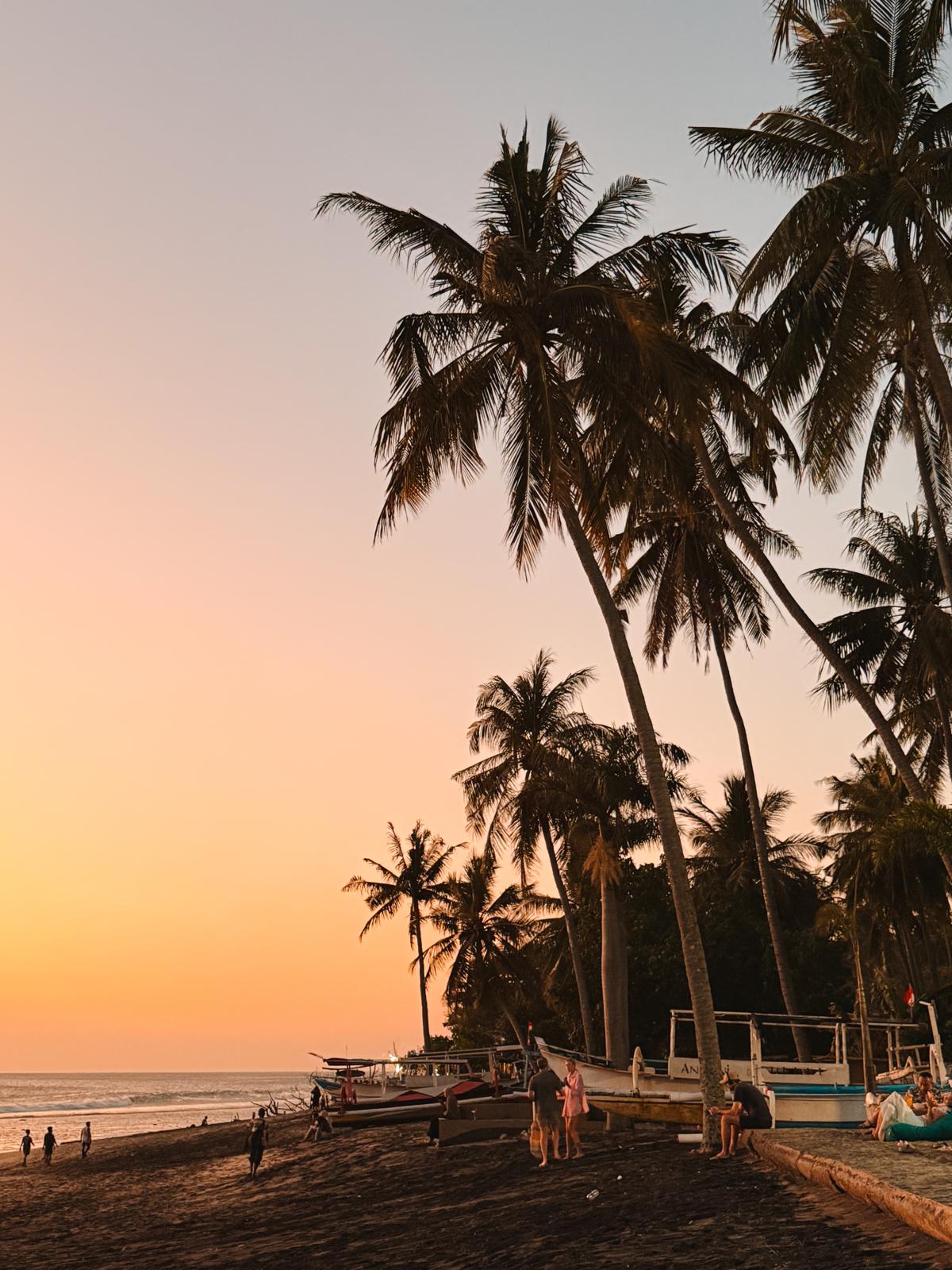 Zwei bunte Cocktails in der Hand, mit Blick auf einen sonnigen Strand und das glitzernde Meer – pure Entspannung im tropischen Paradies.